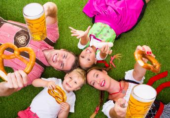 A cheerful family in traditional Bavarian attire, lying on grass, holding pretzels, beer, and sausages, celebrating Oktoberfest with bright smiles, joy, and a festive atmosphere : Stock Photo or Stock Video Download rcfotostock photos, images and assets rcfotostock | RC Photo Stock.: