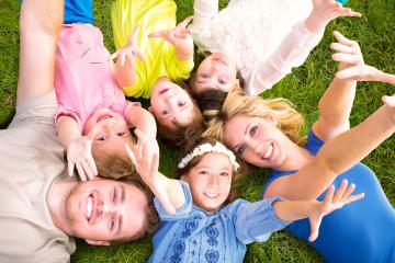 A cheerful family lying on grass in a circle, reaching out with smiles and laughter, enjoying a sunny day outdoors, showcasing love, connection, and fun in a natural setting : Stock Photo or Stock Video Download rcfotostock photos, images and assets rcfotostock | RC Photo Stock.: