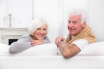 A cheerful senior couple relaxing on a white sofa in a bright and cozy living room, smiling warmly and enjoying a moment of connection and companionship in a peaceful home setting : Stock Photo or Stock Video Download rcfotostock photos, images and assets rcfotostock | RC Photo Stock.: