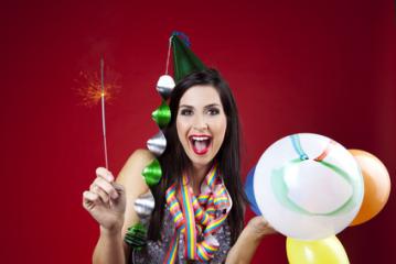 A cheerful woman wearing a party hat and colorful scarf celebrates with balloons and a sparkler, set against a vibrant red background, radiating festive joy and excitement : Stock Photo or Stock Video Download rcfotostock photos, images and assets rcfotostock | RC Photo Stock.: