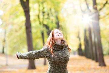 A cheerful woman with red hair wearing a cozy sweater stands in a sunlit autumn park, arms outstretched, enjoying the fresh air and golden leaves, radiating happiness and freedom : Stock Photo or Stock Video Download rcfotostock photos, images and assets rcfotostock | RC Photo Stock.: