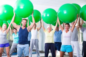 A diverse fitness group in a gym holding green exercise balls over their heads, smiling and engaging in a fun and energetic workout session promoting health and well-being : Stock Photo or Stock Video Download rcfotostock photos, images and assets rcfotostock | RC Photo Stock.: