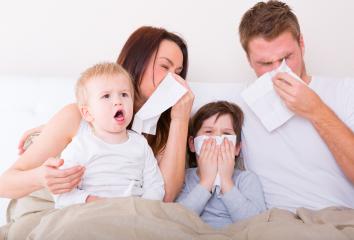 A family of four sitting together, all appearing sick, using tissues for their noses while the youngest child looks upset : Stock Photo or Stock Video Download rcfotostock photos, images and assets rcfotostock | RC Photo Stock.:
