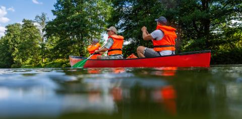 A family of three—a mother, father, and daughter—in life jackets paddling a red canoe on a peaceful river in bavarai, germany. Family on kayak ride. Wild nature and water fun on summer vacation.- Stock Photo or Stock Video of rcfotostock | RC Photo Stock