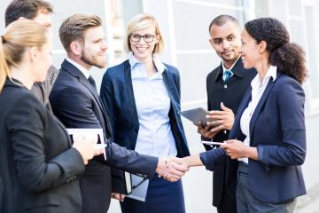 A group of business professionals interacting outdoors, smiling, shaking hands, and holding documents and tablets, symbolizing teamwork, networking, and collaboration in a corporate setting : Stock Photo or Stock Video Download rcfotostock photos, images and assets rcfotostock | RC Photo Stock.: