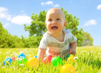 A happy baby crawling on a grassy field with colorful plastic balls scattered around, surrounded by wildflowers under a sunny blue sky and green trees in the background.
- Stock Photo or Stock Video of rcfotostock | RC Photo Stock