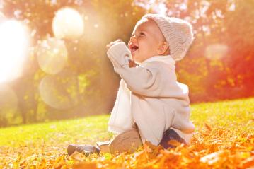 A happy baby sitting outdoors in autumn, surrounded by golden sunlight and falling leaves : Stock Photo or Stock Video Download rcfotostock photos, images and assets rcfotostock | RC Photo Stock.: