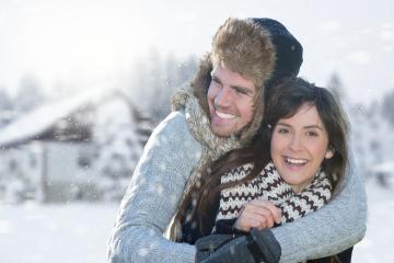 A happy couple bundled in winter clothing, embracing and smiling in a snowy landscape with snowflakes falling and cozy winter cottages in the background, symbolizing love and joy in a winter wonderlan : Stock Photo or Stock Video Download rcfotostock photos, images and assets rcfotostock | RC Photo Stock.: