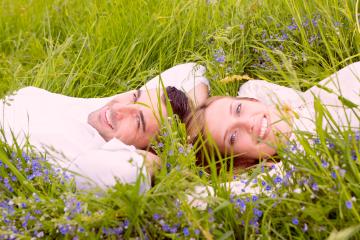 A happy couple lying in a lush green meadow surrounded by wildflowers, enjoying a serene and romantic moment in nature under the warm sunlight : Stock Photo or Stock Video Download rcfotostock photos, images and assets rcfotostock | RC Photo Stock.:
