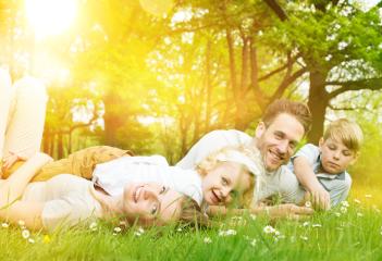 A happy family lying on green grass in a sunny park surrounded by trees, enjoying quality time together, with warm sunlight streaming through the leaves, symbolizing love, joy, and togetherness : Stock Photo or Stock Video Download rcfotostock photos, images and assets rcfotostock | RC Photo Stock.: