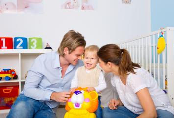 A happy family with parents and their toddler playing with a colorful toy lion in a bright, cheerful nursery with toys, a crib, and vibrant decorations. : Stock Photo or Stock Video Download rcfotostock photos, images and assets rcfotostock | RC Photo Stock.: