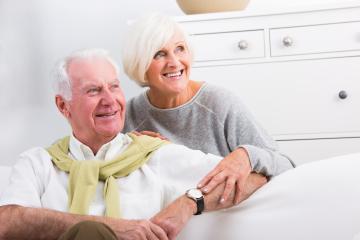 A happy senior couple sitting on a sofa in a bright living room, smiling warmly at each other, symbolizing love, companionship, and a relaxed lifestyle in their golden years : Stock Photo or Stock Video Download rcfotostock photos, images and assets rcfotostock | RC Photo Stock.: