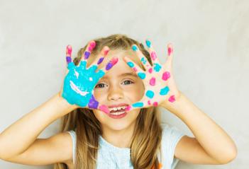 A joyful child with painted hands, showing bright blue, pink, and purple paint, smiling playfully with a creative and fun expression against a simple light background : Stock Photo or Stock Video Download rcfotostock photos, images and assets rcfotostock | RC Photo Stock.: