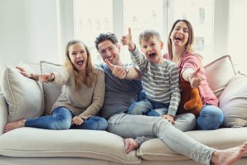 A joyful family sitting on a cozy couch, smiling, laughing, and giving thumbs up in a bright living room, expressing happiness and togetherness : Stock Photo or Stock Video Download rcfotostock photos, images and assets rcfotostock | RC Photo Stock.: