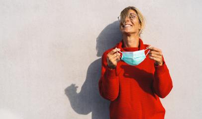 A joyful woman in a bright red sweater removing a light blue face mask, standing against a neutral background, with her shadow visible. Mask freedom after Corona pandemic concept image  : Stock Photo or Stock Video Download rcfotostock photos, images and assets rcfotostock | RC Photo Stock.: