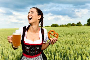 A joyful woman in traditional Bavarian dress holds a mug of beer and a pretzel, laughing in a lush green field under a bright sky, celebrating culture and festivity.
- Stock Photo or Stock Video of rcfotostock | RC Photo Stock