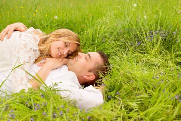 A loving couple lying on lush green grass surrounded by wildflowers, sharing a tender moment with bright smiles, symbolizing love and connection in a natural setting : Stock Photo or Stock Video Download rcfotostock photos, images and assets rcfotostock | RC Photo Stock.: