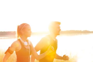 A man and woman jog together during sunrise or sunset near a serene water body, wearing athletic attire, enjoying fitness and the outdoors in a bright, golden sunlight atmosphere : Stock Photo or Stock Video Download rcfotostock photos, images and assets rcfotostock | RC Photo Stock.: