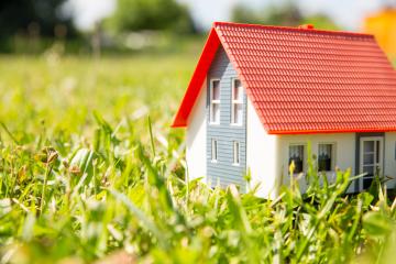 A miniature model house with a red roof and blue siding placed on green grass under bright sunlight, symbolizing real estate, homeownership, or sustainable living in a natural setting : Stock Photo or Stock Video Download rcfotostock photos, images and assets rcfotostock | RC Photo Stock.: