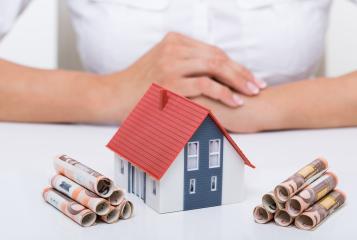 A model house with a red roof surrounded by stacks of rolled euro banknotes on a white table, symbolizing real estate investment, mortgage financing, or savings for a home : Stock Photo or Stock Video Download rcfotostock photos, images and assets rcfotostock | RC Photo Stock.: