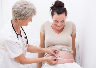 A pregnant woman smiling while a doctor measures her belly with a tape, symbolizing prenatal care, health checkups, and maternity, in a bright and professional healthcare setting- Stock Photo or Stock Video of rcfotostock | RC Photo Stock