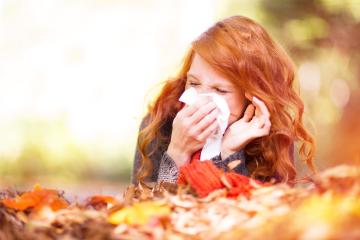 A red-haired woman sneezing into a tissue while sitting among colorful autumn leaves, dressed warmly in a scarf and sweater, with a blurred sunny fall background : Stock Photo or Stock Video Download rcfotostock photos, images and assets rcfotostock | RC Photo Stock.: