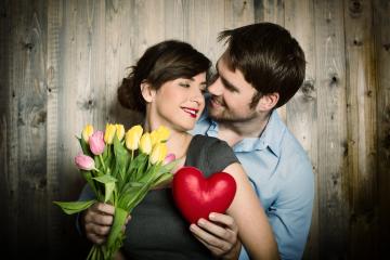 A romantic couple embraces with smiles, holding a bouquet of tulips and a red heart against a rustic wooden backdrop, symbolizing love, affection, and connection : Stock Photo or Stock Video Download rcfotostock photos, images and assets rcfotostock | RC Photo Stock.: