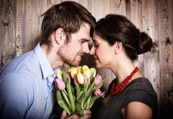 A romantic couple shares an intimate moment with their foreheads touching, holding a colorful bouquet of tulips against a rustic wooden background, expressing love and tenderness : Stock Photo or Stock Video Download rcfotostock photos, images and assets rcfotostock | RC Photo Stock.: