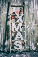 A rustic wooden ladder decorated for Christmas with "XMAS" letters, red ornaments, candy canes, a Santa hat, and small gifts, creating a cozy and festive holiday atmosphere : Stock Photo or Stock Video Download rcfotostock photos, images and assets rcfotostock | RC Photo Stock.: