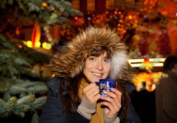 A smiling woman in a cozy fur-lined hood enjoying a hot drink at a festive Christmas market, surrounded by twinkling lights and a holiday ambiance with a decorated tree in the background
 : Stock Photo or Stock Video Download rcfotostock photos, images and assets rcfotostock | RC Photo Stock.: