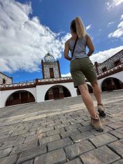 A woman with a ponytail walks on a cobblestone path towards an ornate building with arched doorways and a dome under a partly cloudy blue sky.
- Stock Photo or Stock Video of rcfotostock | RC Photo Stock