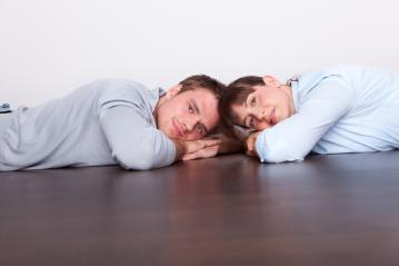 A young couple lying on a dark wooden floor, resting their heads on their hands, gazing forward with relaxed and thoughtful expressions in a minimalist indoor setting
 : Stock Photo or Stock Video Download rcfotostock photos, images and assets rcfotostock | RC Photo Stock.: