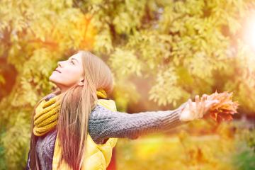 A young woman enjoying autumn, wearing a yellow scarf and vest, holding fall leaves, with sunlight streaming through golden foliage, embracing the peaceful beauty of the season
 : Stock Photo or Stock Video Download rcfotostock photos, images and assets rcfotostock | RC Photo Stock.: