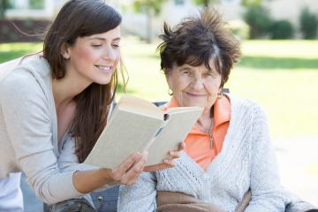 A young woman reading a book to an elderly woman outdoors in a sunny park, sharing a warm and caring moment, symbolizing intergenerational connection and support : Stock Photo or Stock Video Download rcfotostock photos, images and assets rcfotostock | RC Photo Stock.: