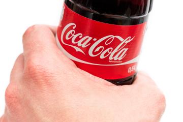 AACHEN, GERMANY OCTOBER, 2017: Hand hold a bottle Coca-Cola on white background. Coca Cola drinks are produced and manufactured by The Coca-Cola Company.- Stock Photo or Stock Video of rcfotostock | RC-Photo-Stock