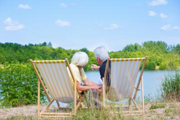 An elderly couple sitting on striped deck chairs by a serene lake, surrounded by lush greenery under a bright blue sky, enjoying a peaceful and relaxing moment in nature
 : Stock Photo or Stock Video Download rcfotostock photos, images and assets rcfotostock | RC Photo Stock.: