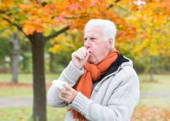 An elderly man coughing into his hand in an autumn park, wearing a warm scarf and sweater, surrounded by vibrant orange foliage, symbolizing seasonal health challenges and cooler weather : Stock Photo or Stock Video Download rcfotostock photos, images and assets rcfotostock | RC Photo Stock.: