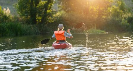 Back view of a woman paddling a kayak on a river, surrounded by lush greenery and bathed in sunset light. Kayak Water Sports concept image- Stock Photo or Stock Video of rcfotostock | RC Photo Stock