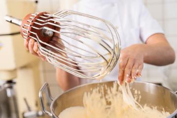 baker cleans batter off a large whisk attachment over a mixing bowl, showcasing the process of preparing batter in a professional kitchen environment : Stock Photo or Stock Video Download rcfotostock photos, images and assets rcfotostock | RC Photo Stock.: