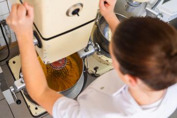 baker operates a commercial stand mixer, mixing a batter or dough. The mixing bowl is filled with a yellow-orange mixture, and the baker is adjusting the machine's settings- Stock Photo or Stock Video of rcfotostock | RC Photo Stock