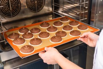 baker places a tray of raw gingerbread rounds on baking wafers into the oven for baking, showcasing the preparation process in a professional bakery kitchen setting- Stock Photo or Stock Video of rcfotostock | RC Photo Stock