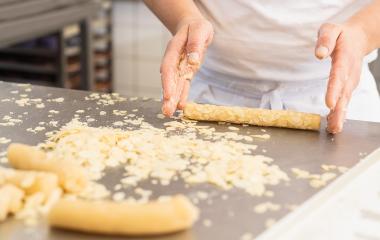 Baker rolling cookie dough in almond slices on a work surface in a bakery, preparing the dough for baking with hands covered in almond flakes in a professional baking environment- Stock Photo or Stock Video of rcfotostock | RC Photo Stock