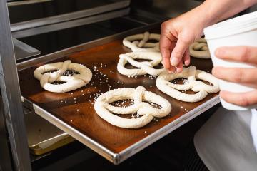 Baker salting raw pretzels on a baking sheet- Stock Photo or Stock Video of rcfotostock | RC Photo Stock