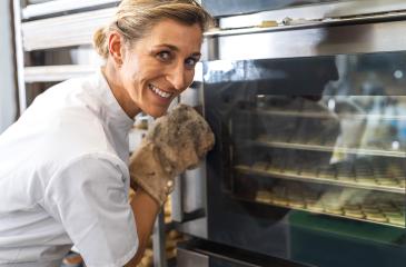 baker smiles while checking on the baking cookies through the oven door, wearing a glove for safety. The scene captures the joy and dedication involved in baking. : Stock Photo or Stock Video Download rcfotostock photos, images and assets rcfotostock | RC Photo Stock.: