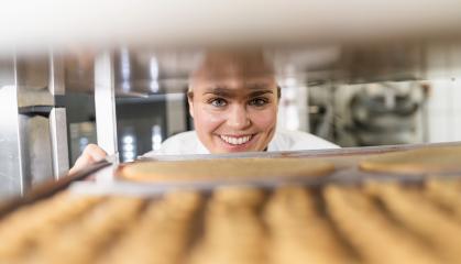 Baker smiling while checking trays of freshly baked cookies on a cooling rack in a bakery, inspecting the baked goods in a professional baking environment : Stock Photo or Stock Video Download rcfotostock photos, images and assets rcfotostock | RC Photo Stock.: