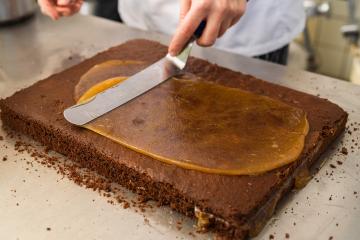 Baker spreading caramel on a chocolate cake layer using a spatula in a bakery, preparing the cake for layering in a professional baking environment : Stock Photo or Stock Video Download rcfotostock photos, images and assets rcfotostock | RC Photo Stock.: