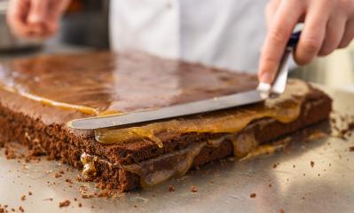 Baker spreading caramel on a chocolate cake layer with a spatula in a bakery, carefully smoothing the filling in preparation for the next layer in a professional baking environment : Stock Photo or Stock Video Download rcfotostock photos, images and assets rcfotostock | RC Photo Stock.: