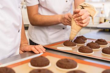 baker uses a piping bag to add gingerbread dough onto wafers placed on a baking sheet, preparing the cookies for baking in a professional kitchen with a colleague observing : Stock Photo or Stock Video Download rcfotostock photos, images and assets rcfotostock | RC Photo Stock.: