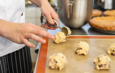 baker uses a scoop to portion cookie dough onto a baking sheet, preparing the cookies for baking. The scene captures the precision and care in the baking process. : Stock Photo or Stock Video Download rcfotostock photos, images and assets rcfotostock | RC Photo Stock.: