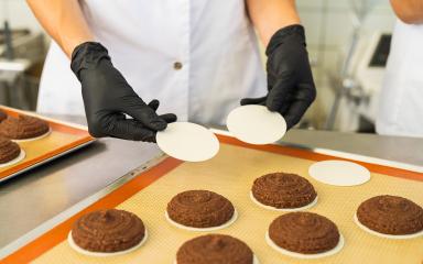 baker wearing black gloves carefully places wafers under gingerbread cookies on a baking tray, preparing the treats for the oven in a professional bakery setting : Stock Photo or Stock Video Download rcfotostock photos, images and assets rcfotostock | RC Photo Stock.: